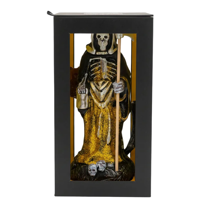 Statue of a skeleton in a robe with a staff inside a black box on a white background