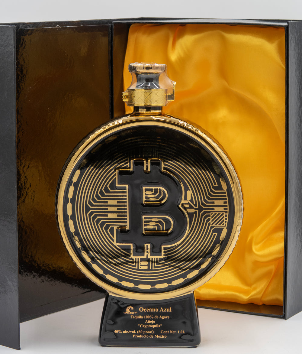 Decorative item with Bitcoin symbol in a black and gold design, placed in a box with yellow satin lining.