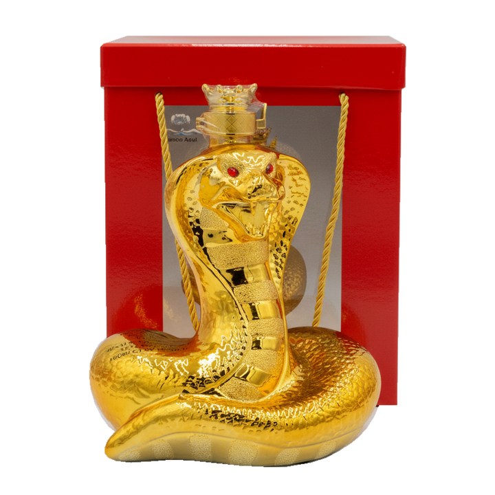 Gold snake-shaped bottle with red eyes in front of a red box on a white background