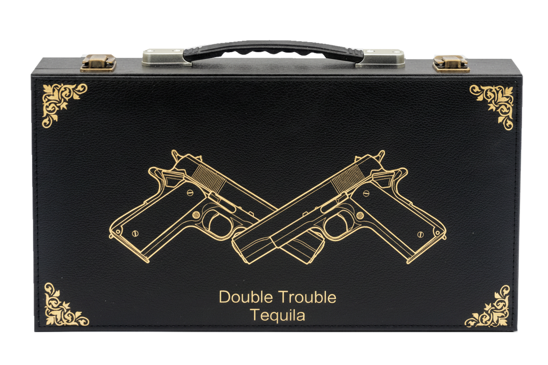 Black tequila box with gold embossed design of two crossed guns and 'Double Trouble Tequila' text on a white background.