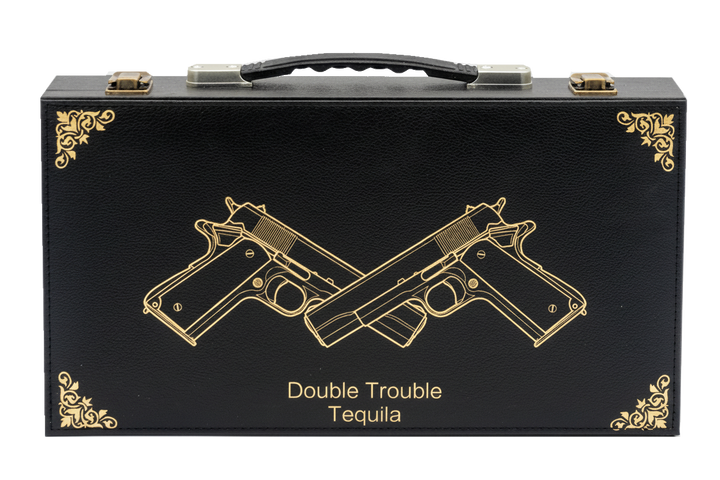 Black tequila box with gold embossed design of two crossed guns and 'Double Trouble Tequila' text on a white background.