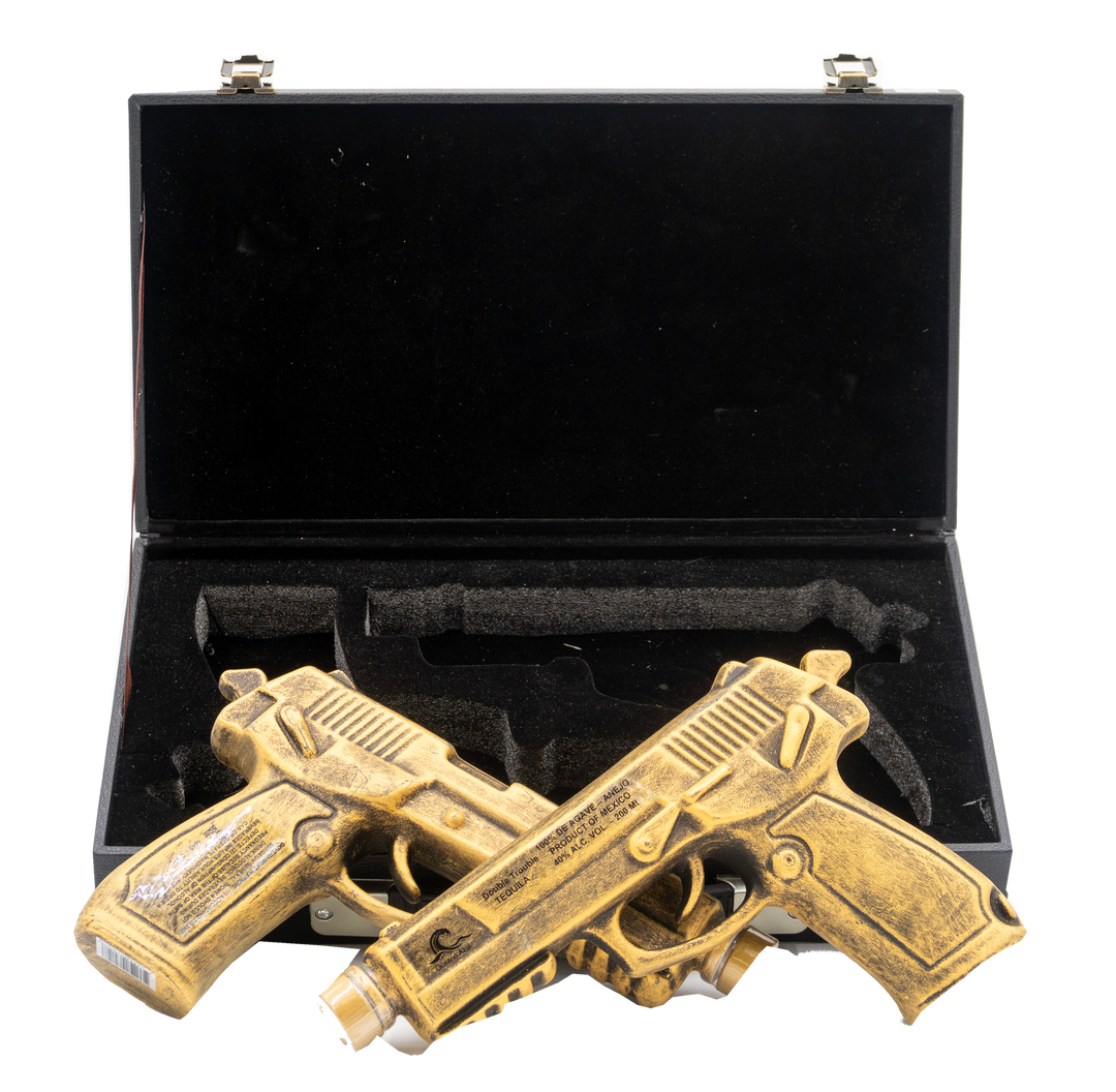 Two brass guns in a black case on a white background