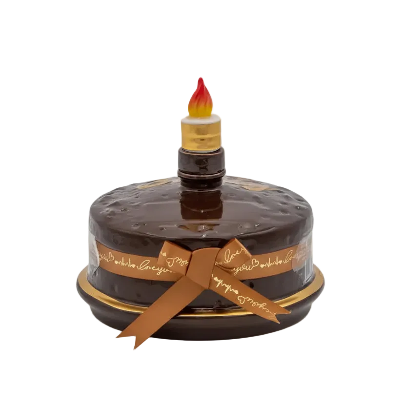 Oceano Azul round chocolate-colored La Cake bottle with gold trim, ribbon, and candle-shaped stopper.