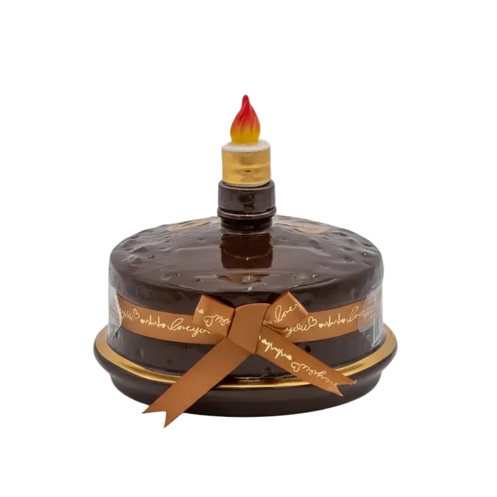Oceano Azul round chocolate-colored La Cake bottle with gold trim, ribbon, and candle-shaped stopper.