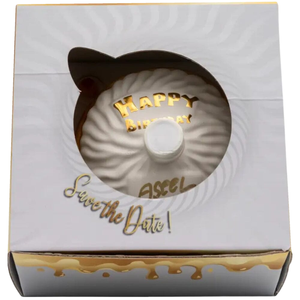 Oceano Azul round white La Cake bottle viewed through the window of its closed white-and-gold presentation box.