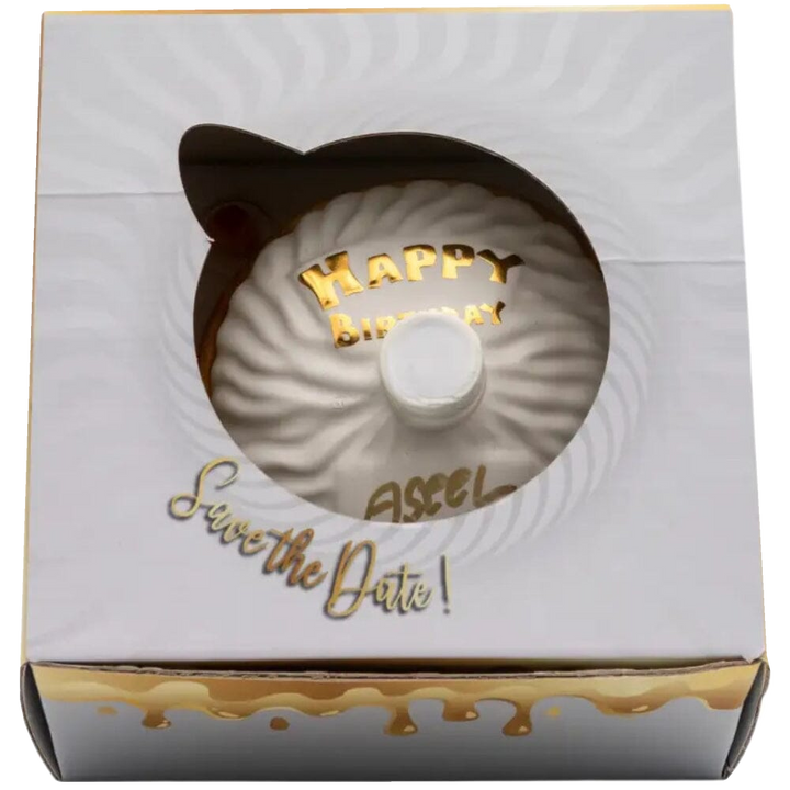 Oceano Azul round white La Cake bottle viewed through the window of its closed white-and-gold presentation box.